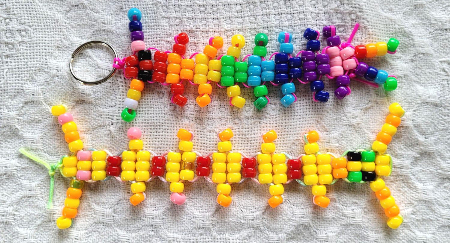 Two centipedes made of pony beads, one rainbow and one yellow with red stripes