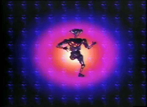 A humanoid robot jerking around a bright screen which fades from yellow to pink to dark blue.