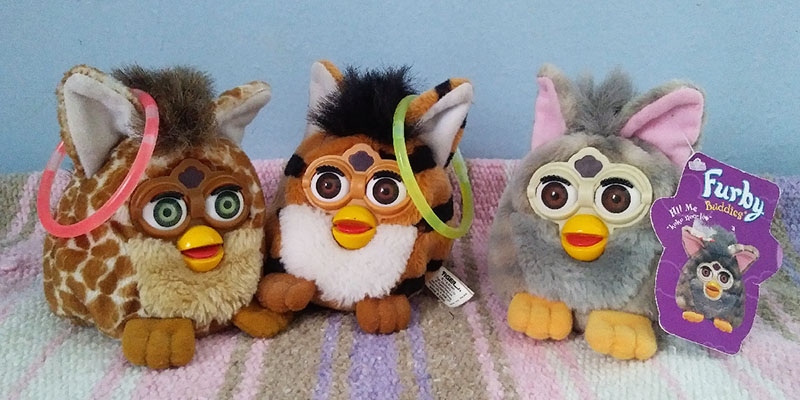 Three Furby toys in assorted animal patterns- a giraffe, tiger, and wolf