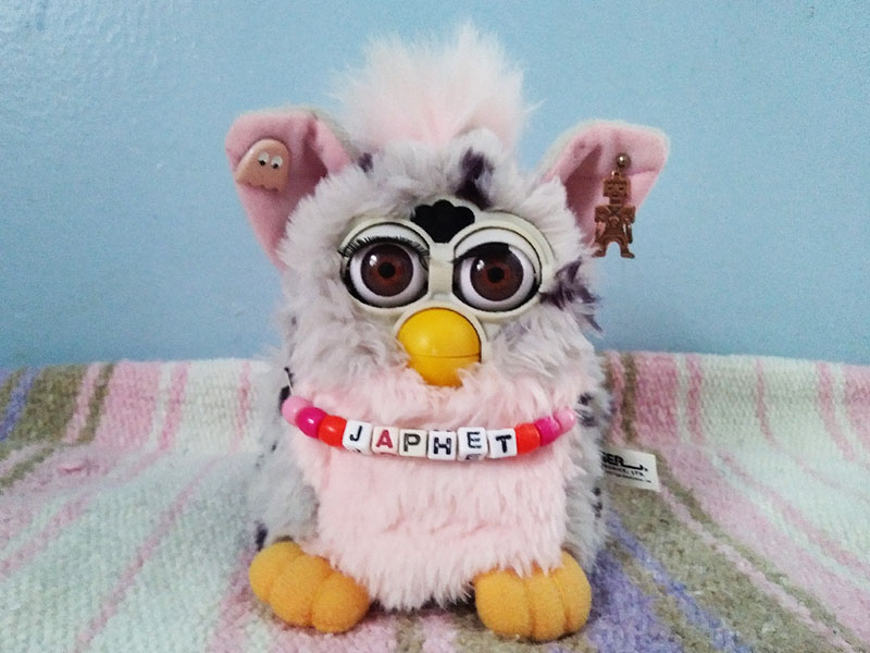 A grey and black Furby with a pink tummy