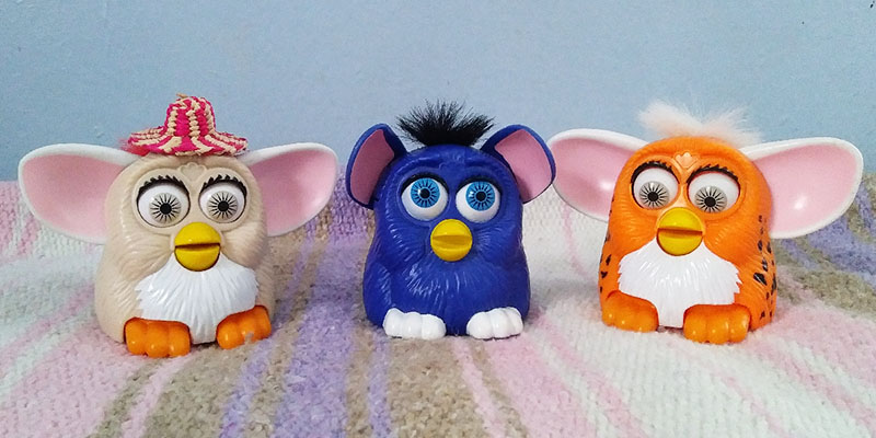 Three small plastic Furby toys- one tan, blue, and leopard-print