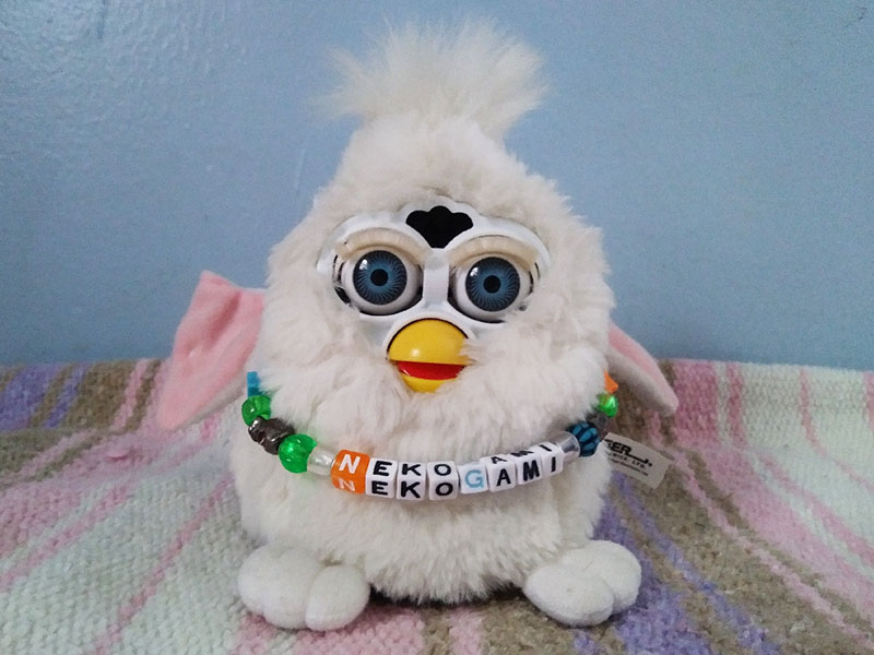 A white Furby with his ears disconnected
