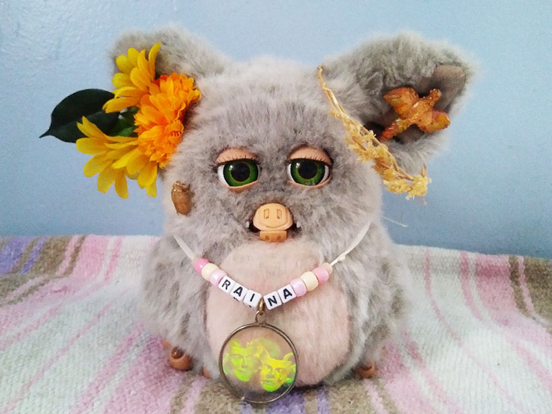A large grey Furby with flowers in her ears